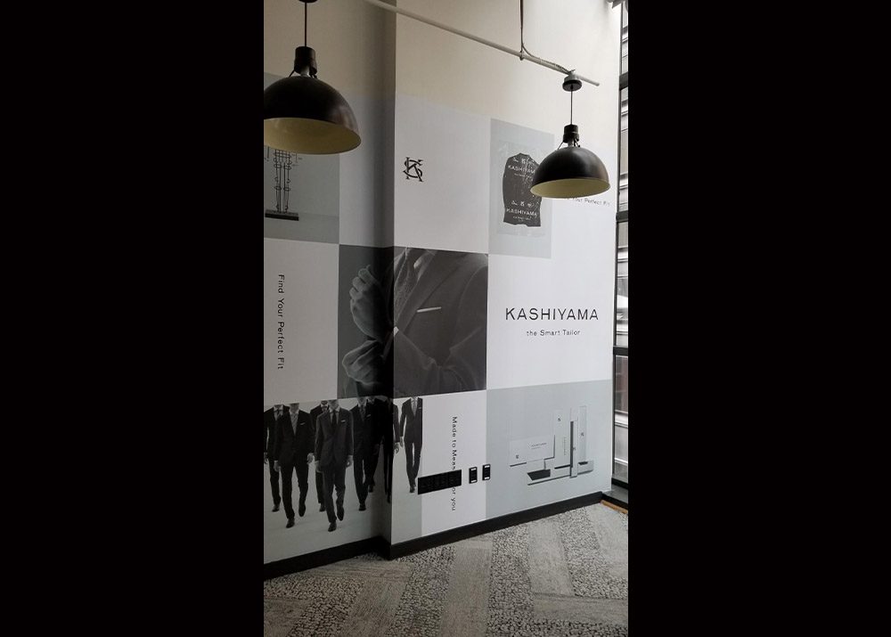 wall covering installation inside a tailor shop promoting the brand with photos of suits and the company logo