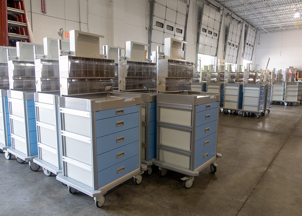 blue medical supply carts with drawers assembled in a warehouse