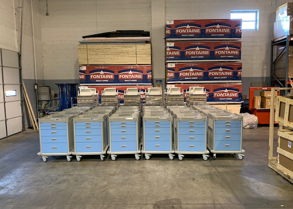 30 blue medical carts with drawers assembled in a warehouse
