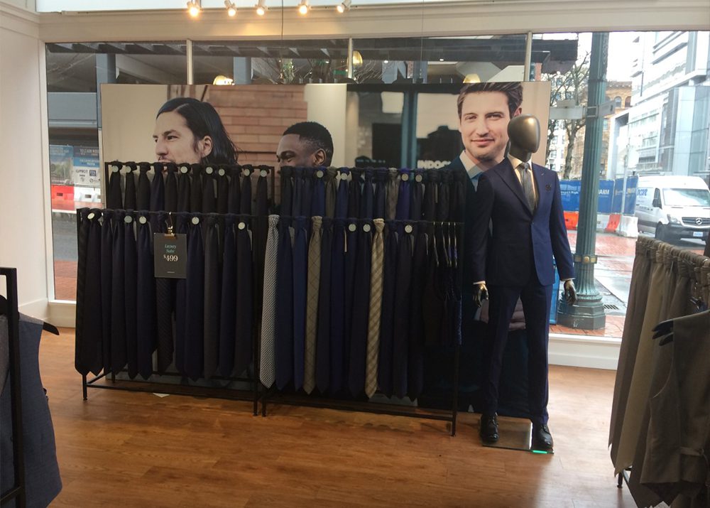 large retail graphics install showing men in suits behind tie rack fixture
