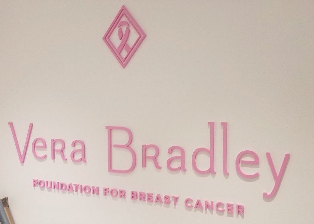 pink plastic Vera Bradley logo sign installed on wall